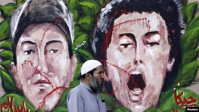 An anti-Mursi protester walks past graffiti depicting two activists who died recently, at Tahrir Square in Cairo December 10, 2012.