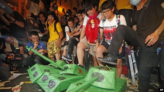 Pro-democracy protesters step on the mock Chinese PLA tanks after tens of thousands people march at a down town street during the annual pro-democracy protest in Hong Kong, July 1, 2012. 