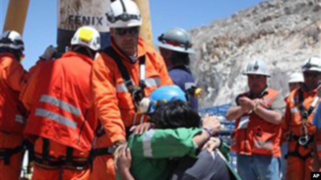 In this photo released by the Government of Chile, miner Omar Reygadas Rojas, kneeling in green, embraces his son after being rescued from the collapsed San Jose gold and copper mine, near Copiapo, Chile, Wednesday, Oct. 13, 2010.