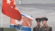 North Korean soldiers chat as they stand guard behind national flags of China (front) and North Korea on a boat anchored along the banks of Yalu River, near the North Korean town of Sinuiju, opposite the Chinese border city of Dandong, June 10, 2013. 