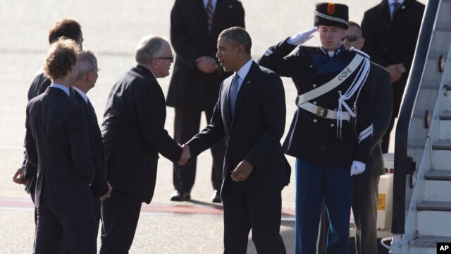 President Barack Obama, right, is greeted by Dutch Foreign Minister Frans Timmermans, left, upon arrival at Schiphol Amsterdam Airport, Netherlands, March 24, 2014.