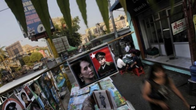 In this photo taken on Feb 23, 2012, people walk past a roadside stall selling the posters of Burmese democracy icon Aung San Suu Kyi and her late father in Rangoon, Burma. 