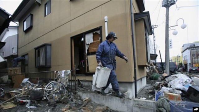 A resident cleans up tsunami debris in his destroyed house Tuesday, March 15, 2011, in Soma city, Fukushima prefecture, Japan.