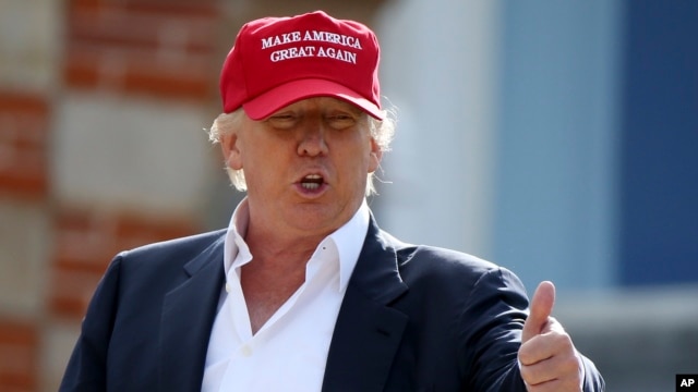 Donald Trump habla conlos periodistas luego de llegar en helicóptero al Abierto Británico de Golf, en Escocia. El letrero en su gorra lee: 