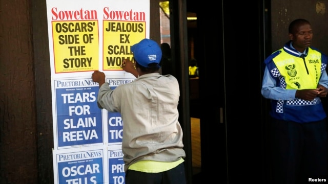A newspaper vendor puts up posters outside the Pretoria Magistrates court where Oscar Pistorius appeared for a bail hearing, February 20, 2013.