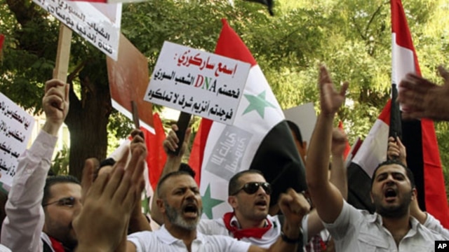 Pro-Syrian regime protesters, shout slogans and hold up an Arabic placard read:"Listen Sarkozy you checked the Syrian people's DNA and you found cells of honor that you don't have," as they protest in front the EU mission office, in Damascus, Sept. 29, 20