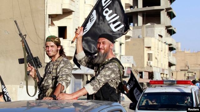 Militant Islamist fighters wave flags as they take part in a military parade along the streets of Syria's northern Raqqa province, June 30, 2014.