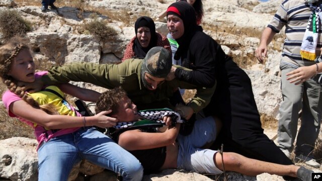 FILE - In this Aug, 28, 2015 photo, Palestinian women and girls scuffle with an Israeli soldier trying to arrest a 12-year-old boy during a protest near the West Bank village of Nebi Saleh.