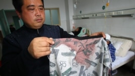 Man displays a blood stained coat in a hospital after his son was stabbed during a knife attack that took place on December 14, 2012 at a primary school in Guangshan county, central China's Henan province. 