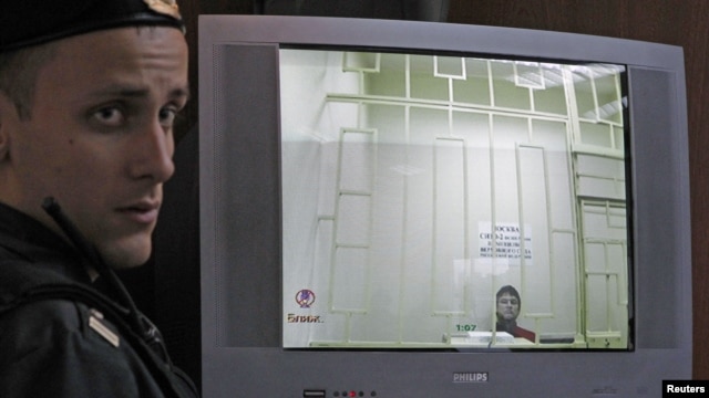 A bailiff stands next to a screen with a live broadcast of opposition activist Leonid Razvozzhayev's appeal at a Moscow court hearing, November 7, 2012.