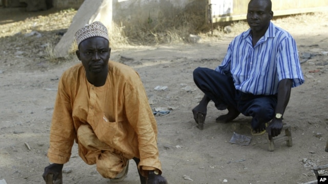 Polio sufferers Yusuf  Umar, right, and Aminu Ahmed use wooden blocks to propel themselves through the dusty streets of Kano, Nigeria, November 28, 2008. 