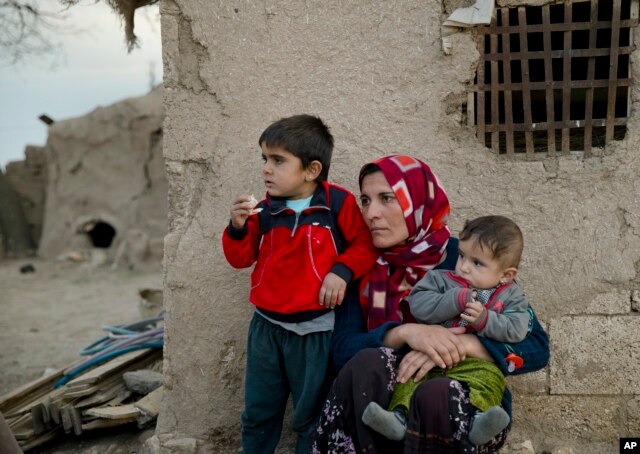 FILE - Members of a Syrian Kurdish refugee family from Kobani sit in the village of Alanyurt on the Turkish side of the Turkey-Syria border.