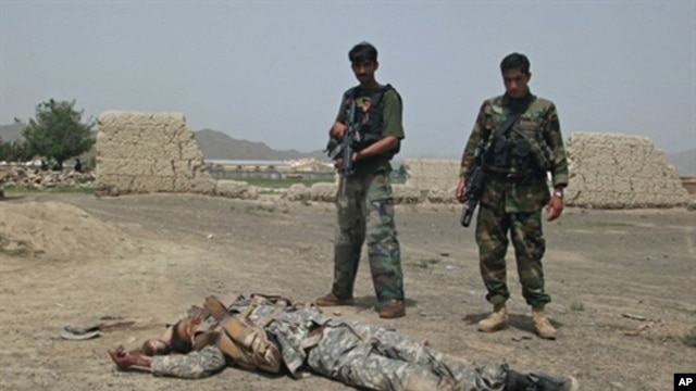 Afghan National Army (ANA) soldiers stand guard near the body of a suicide attacker near US military camp Salerno on the outskirts of Khost city, 28 Aug 2010