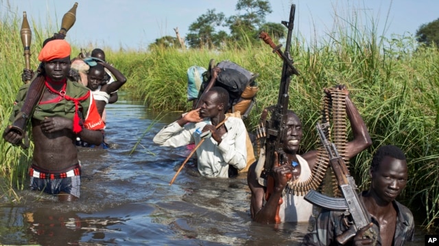 Rebel soldiers patrol and protect civilians from the Nuer ethnic group as the civilians walk through flooded areas to reach a camp for the displaced in the town of Bentiu, South Sudan. More than 2 million South Sudanese have been displaced by 18 months of fighting.