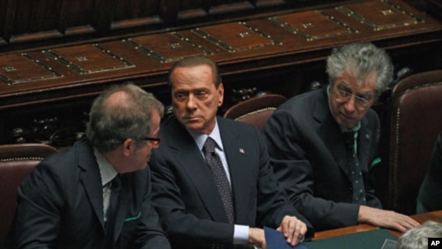 Italian Prime Minister Silvio Berlusconi (C) holds and saves a memo reading "308 [the result of the vote] - 8 traitors - political reversal - vote - take note: resign - Republic President - a solution" during a budget vote at the parliament in Rome, Novem