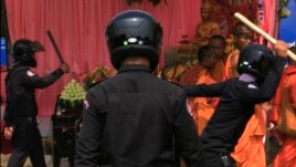 Security officers try to beat Buddhist monks who took part in a rally of the Cambodian National Rescue Party in Phnom Penh, Cambodia, Saturday, Jan. 4, 2014.