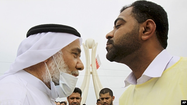 Hassan Mushaima, a Bahraini rights activist and a prominent Shi'ite opposition leader, wears a mask against tear gas as he is greeted by an anti-government demonstrator at Pearl roundabout in Manama, Bahrain, March 13, 2011