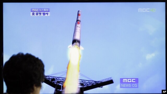 Una mujer en Corea del Sur mira el lanzamiento del cohete por parte de Corea del Norte, un minuto después la nave se despedazó en el aire.