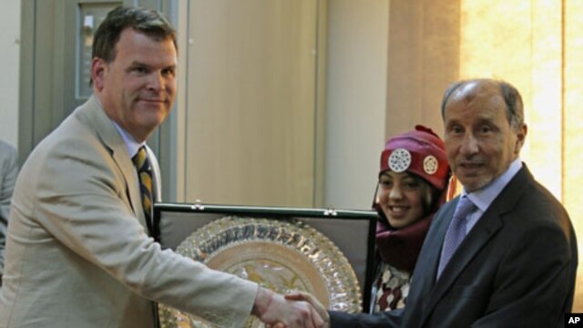 Canada's Foreign Minister John Baird (L) exchanges gifts with the head of Libya's National Transitional Council Mustafa Abdel Jalil, during his first visit to the rebel-held city of Benghazi, June 27, 2011