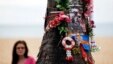 A woman looks at a tree decorated with flowers and pictures as people gather for a Swedish memorial service for victims of the 2004 tsunami at a beach in Khao Lak December 26, 2014. 