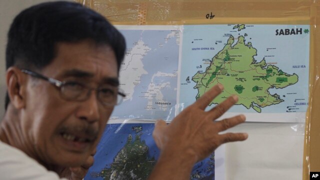Abraham Idjirani, spokesman for the Sultanate of Sulu, points at a map of Borneo's eastern Sabah state as he talks to reporters in suburban Taguig, south of Manila, Philippines, March 5, 2013.