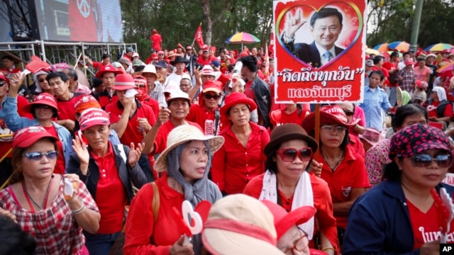 Pro-government protesters show a portrait of former Prime Minister Thaksin Shinawatra during a rally in Aksa, outskirt of  Bangkok, Thailand, Saturday, May 10, 2014.