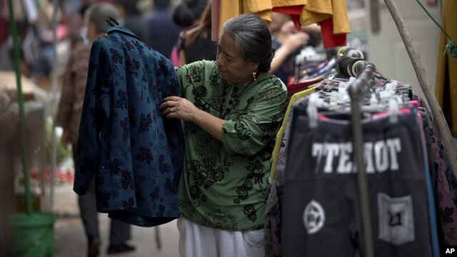 A woman checks a jacket for sale at an open market along a Hutong alley in Beijing, China, September 9, 2012. 