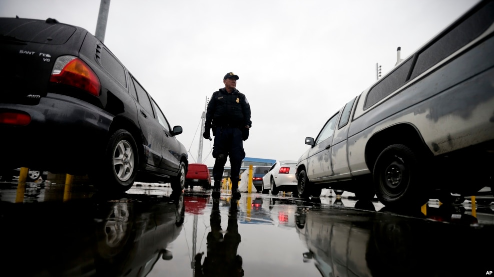 Nhân viên của Cơ quan Hải quan và Biên phòng Mỹ đứng canh gác trong lúc xe cộ xếp hàng vào nước Mỹ từ Tijuana, Mexico.