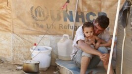 A Syrian refugee holds his child as he sits by his tent at Al Zaatri refugee camp in the Jordanian city of Mafraq, near the border with Syria, Sept. 9, 2012. 