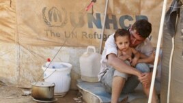 A Syrian refugee holds his child as he sits by his tent at Al Zaatri refugee camp in the Jordanian city of Mafraq, near the border with Syria, September 9, 2012. 