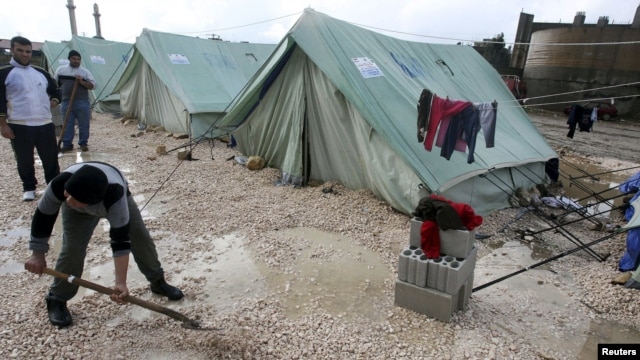 Syrian refugees shovel away water pooled outside their tents after heavy rain, at a center funded by the International Islamic Relief Organization of Saudi Arabia (IIROSA), which provides shelter for Syrian refugees in al-Marj, in the Bekaa valley, Lebanon, January 7, 2013.