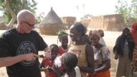 Dave Stahl helps children pump their soccer balls in Niger