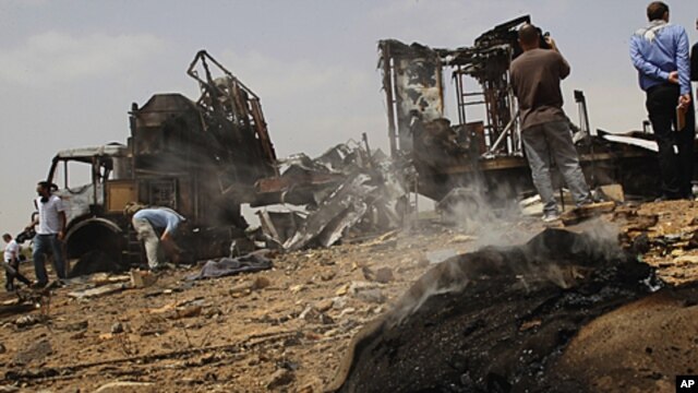 In this photo taken on a organized government tour, foreign journalists take photographs next to a damaged truck at the Hadba agricultural area, outside Tripoli, Libya, on June 8, 2011, which Libyan officials claim was a target of a NATO air strike.