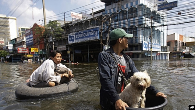 A Thai resident uses a makeshift float to keep his dog dry as he pulls a woman along flooded streets in Rangsit district at the outskirts of Bangkok, Thailand, October 21, 2011.
