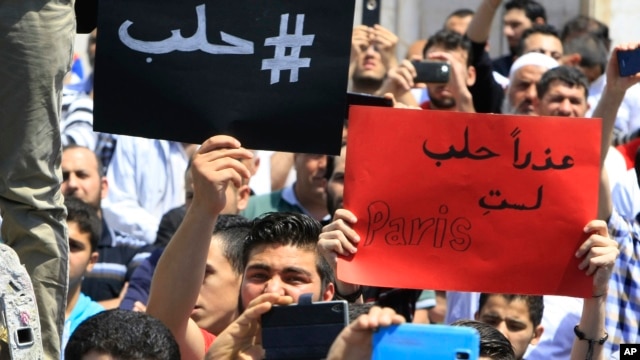 Người biểu tình Lebanon cầm những tấm bảng tiếng Ả Rập với nội dung "#Aleppo" (trái) và "Xin lỗi, Aleppo, các bạn không phải là Paris" (phải) trong một cuộc biểu tình thể hiện tình đoàn kết với Aleppo ở Sidon, Lebanon, ngày 06 tháng 5 năm 2016.