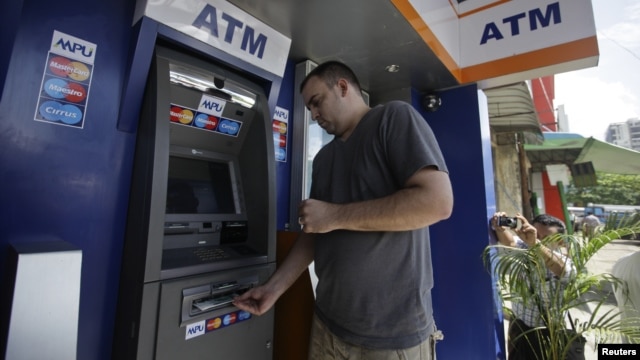 American tourist Ryan Russell withdraws cash from an ATM machine using a MasterCard card, the first such ATM transaction, Rangoon, Burma, November 15, 2012.  