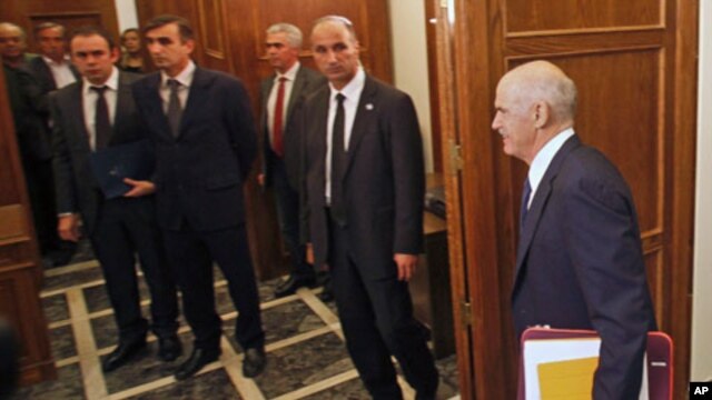 Aides and security officers watch as Greek Prime Minister George Papandreou arrives at an urgent cabinet meeting in the Greek parliament in Athens, Greece, November 3, 2011.