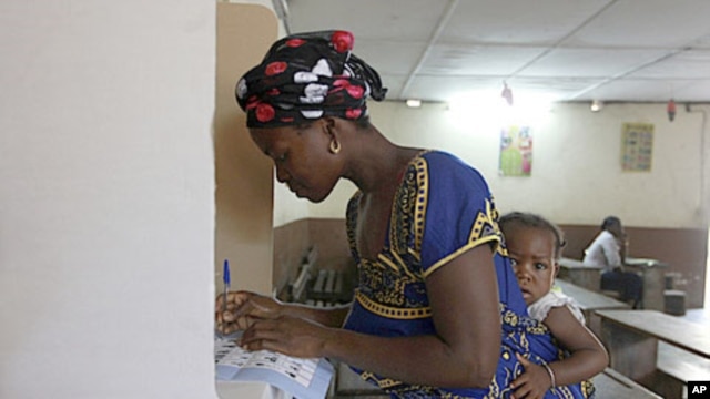 A woman with a baby on her back, votes at a polling station in Abidjan, Ivory Coast, December 11, 2011.