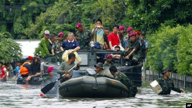 Para anggota marinir melakukan evakuasi beberapa warga yang terjebak banjir di Jakarta, Minggu (20/1).