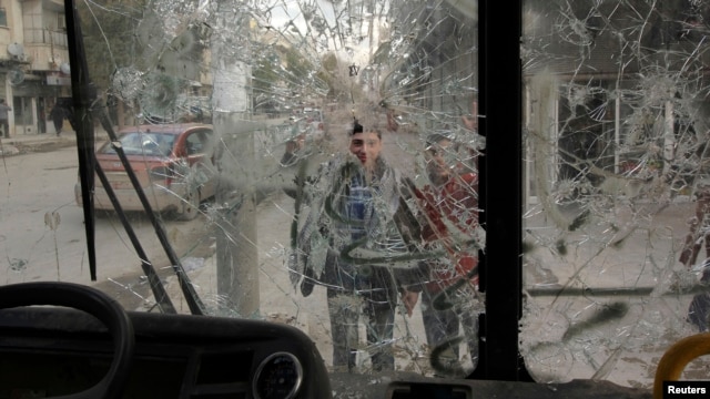 Boys are pictured through a broken windshield as they stand on a street in Aleppo, Feb. 28, 2013.