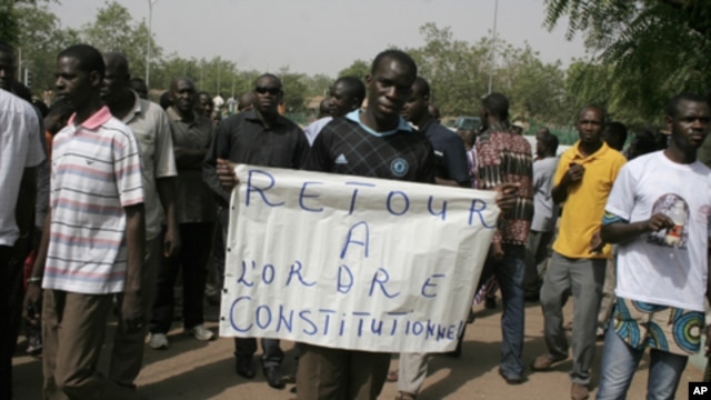 A man carries a sign reading 'Return to constitutional order,' as people gather in protest against the recent military coup, in Bamako, Mali on Monday, March 26, 2012.