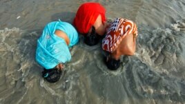 Các phụ nữ đạo Hindu đi hành hương nhúng đầu xuống nước sông Hằng 