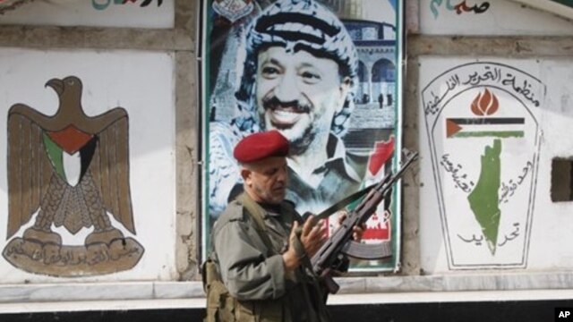PLO security officer in front of a portrait of the late Palestinian leader at camp Ein el-Hilweh, Sidon, Lebanon, June 19, 2012.
