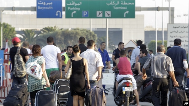 Travelers carry their luggage, as they walk towards the Beirut Rafik Hariri international airport after some of the families of 11 Lebanese pilgrims kidnapped in Syria blocked the highway leading to Beirut airport to protest the Lebanese government's fail