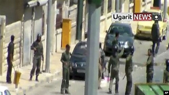 Image made from amateur video released by Ugarit News and accessed via AP TV News on Aug. 8, 2011, shows members of the Syrian military standing near the body of man in the northern Syrian province of Idlib Sunday Aug. 7, 2011. (Contents and date cannot b