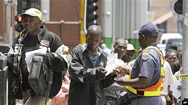 Zimbabweans pass a police cordon to submit their application forms in a last-minute bid to have their status in South Africa legalized, outside the Immigration offices in Johannesburg, Dec 31, 2010