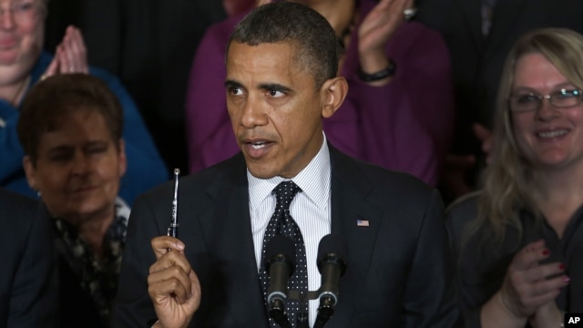 President Barack Obama holds up a pen as he speaks about the economy and the deficit in the East Room of the White House in Washington, November 9, 2012.