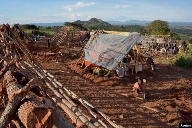 FILE - A Mozambican child plays with a hoe outside a makeshift shelter at Kapise camp in Malawi's Mwanza district, Jan. 18, 2016.