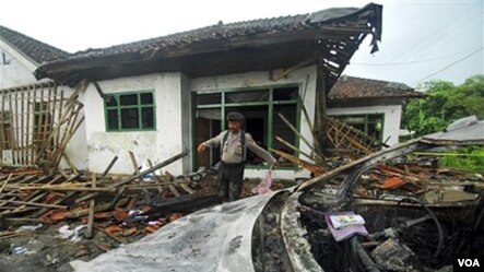 Seorang polisi menginspeksi kerusakan rumah  seorang jemaah Ahmadiyah di Cikeusik setelah  serangan massal yang menewaskan tiga orang, Feb, 2011. Setelah peristiwa Cikeusik, kekerasan terhadap warga Ahmadiyah terus meningkat (foto,dok) 