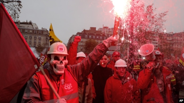 Union members hold safety flares during a demonstration in front of the entrance of the Paris auto show in Paris, Tuesday, Oct. 9, 2012. 